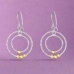 Load image into Gallery viewer, A pair of silver earrings with gold accents in a circular link design, hanging from fish hook closures.