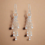 Load image into Gallery viewer, A pair of 925 sterling silver hoop earrings with a geometric pattern, dangling and sparkling in light.
