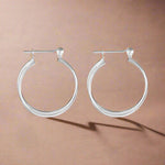 Load image into Gallery viewer, A pair of intertwined plain silver hoop earrings.