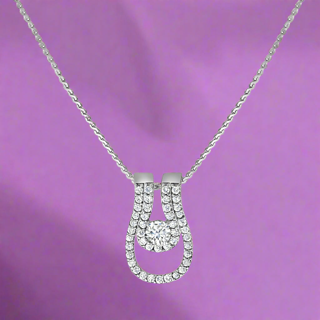A silver pendant featuring a cubic zirconia centerpiece with additional clear cubic zirconia stones set around it, attached to a silver chain.