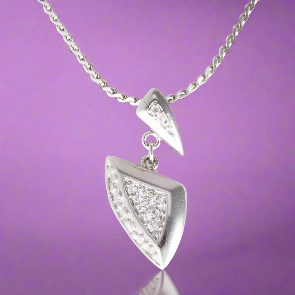 A silver pendant featuring a geometric design with cubic zirconia accents, attached to a silver chain.