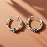 Load image into Gallery viewer, Pair of silver hoop earrings on a white background
