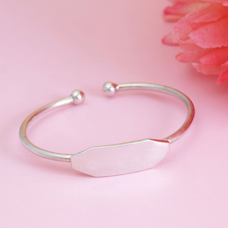 Silver bracelet with a pink stone on a pink background