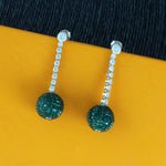 Load image into Gallery viewer, Green beaded earrings with silver accents on a yellow and black textured background
