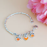 Load image into Gallery viewer, Silver bracelet with charms on a beige background with pink flowers
