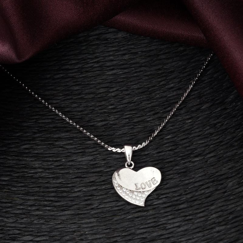 Silver heart-shaped pendant with 'LOVE' engraving on a dark textured surface