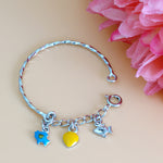 Load image into Gallery viewer, Silver bracelet with charms on a beige background with pink flowers
