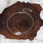 Load image into Gallery viewer, Silver bracelet with a decorative clasp on a wooden surface
