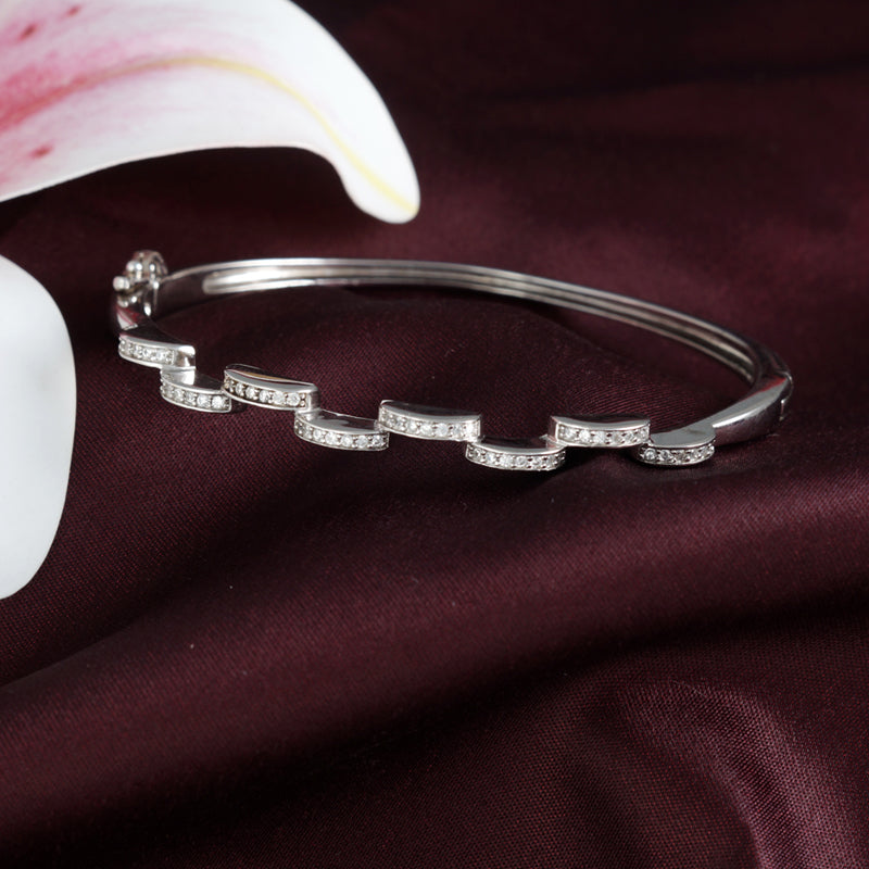 Silver bracelet with diamond accents on a dark fabric background