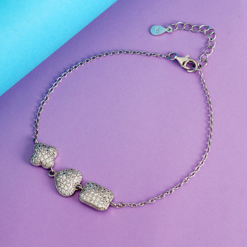 Silver bracelet with heart-shaped charms on a purple and blue background