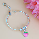 Load image into Gallery viewer, Silver bracelet with a pink strawberry charm on a beige background with pink flowers.
