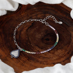Load image into Gallery viewer, Multicolored beaded bracelet with a heart charm on a wooden surface
