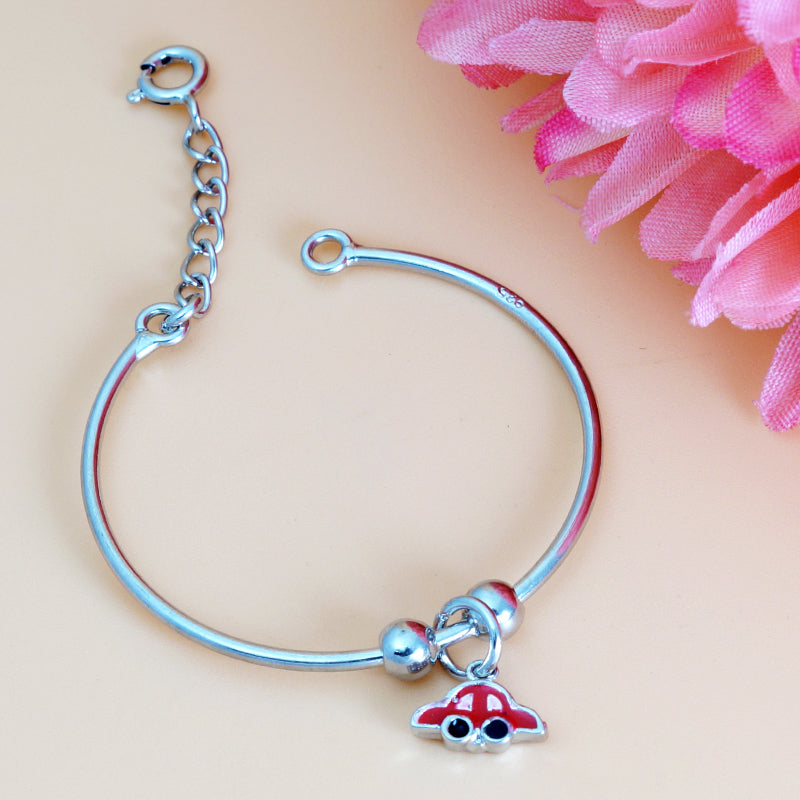 Silver bracelet with a red and blue charm on a pink background