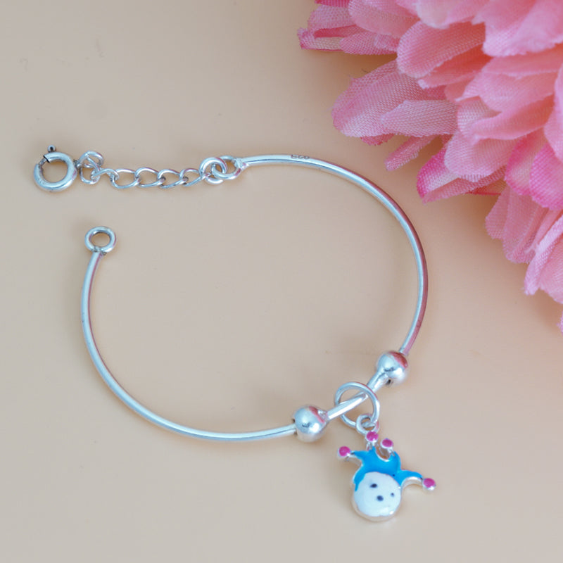 Silver bracelet with a small charm on a beige background with pink flowers