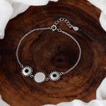 Load image into Gallery viewer, Silver bracelet with gear-shaped charms on a wooden surface
