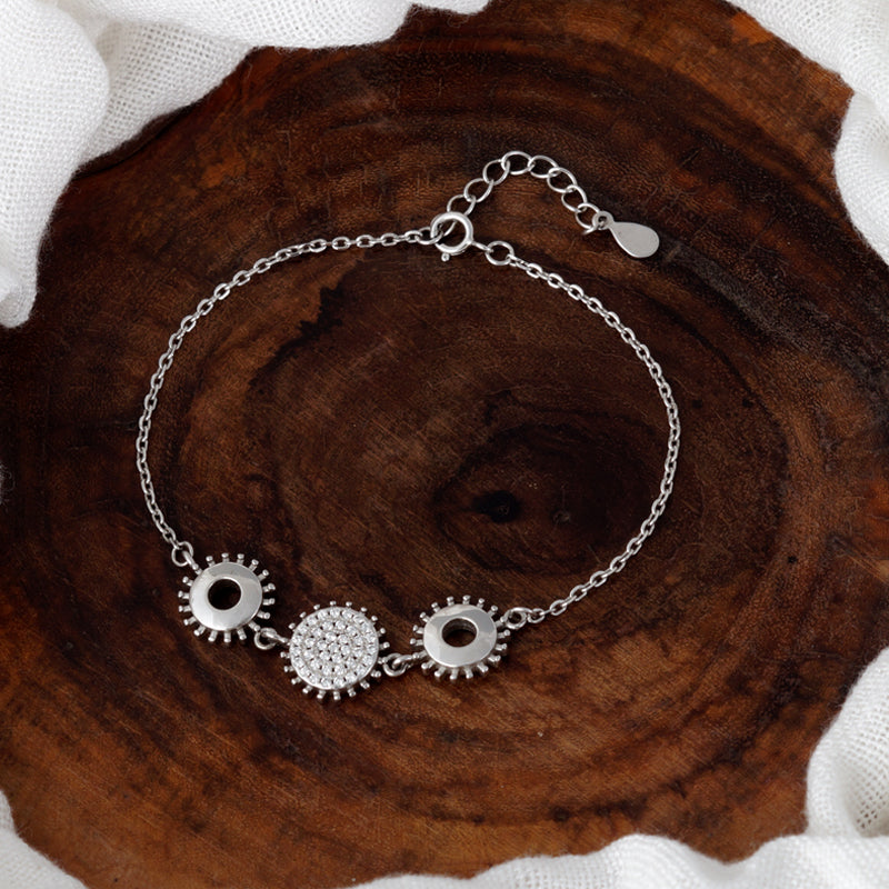 Silver bracelet with gear-shaped charms on a wooden surface