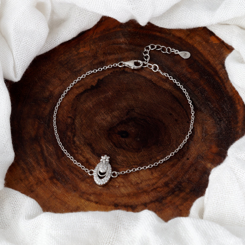 Silver bracelet with a heart-shaped clasp on a wooden surface