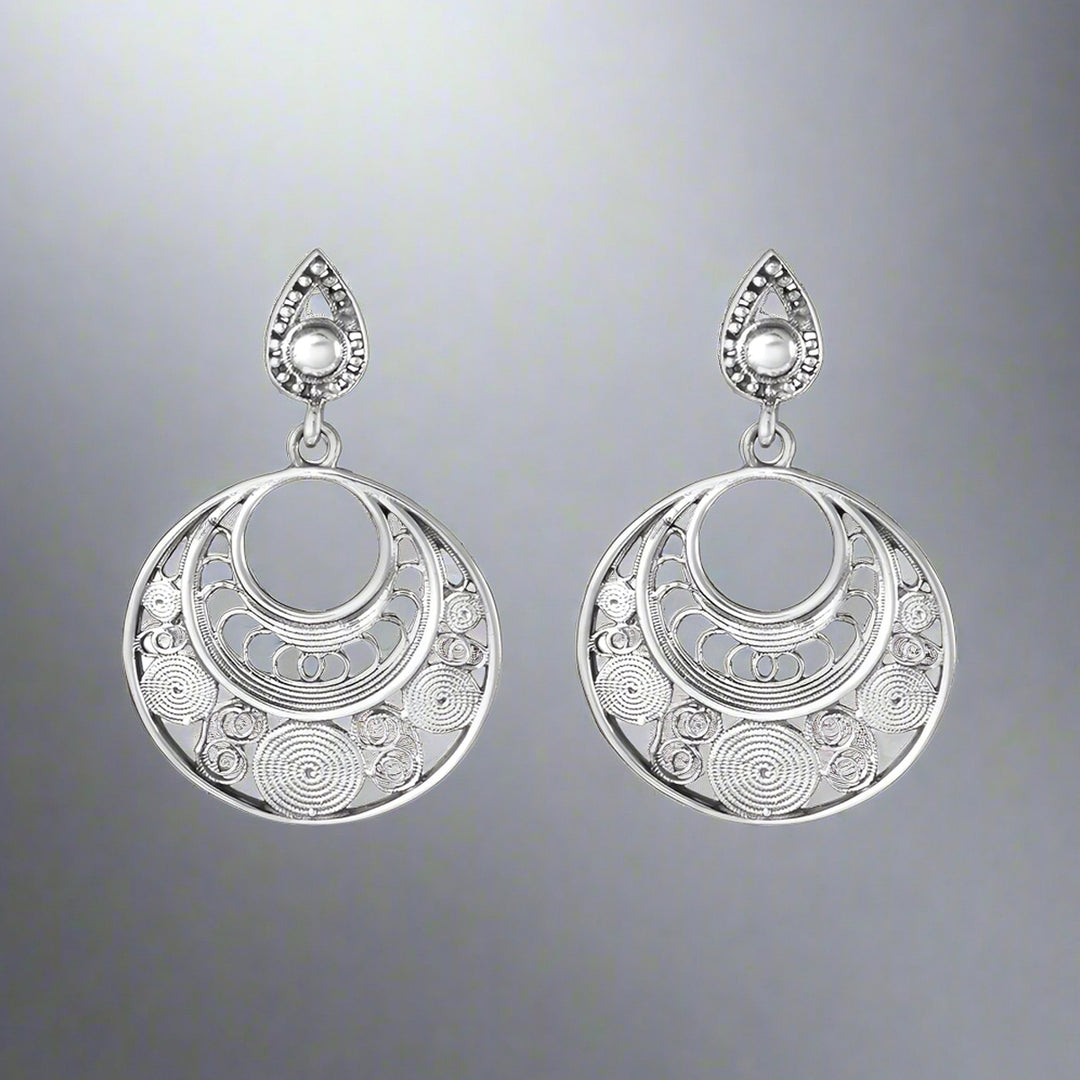 Pair of silver earrings with intricate designs on a gray background