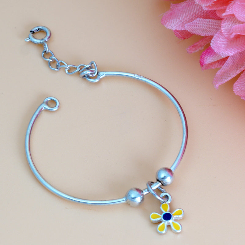 Silver bracelet with a colorful flower charm on a pink floral background