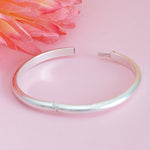 Load image into Gallery viewer, Silver bangle on a pink background with decorative fabric
