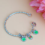 Load image into Gallery viewer, Silver bracelet with frog-themed charms on a beige background
