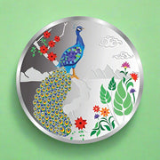 A silver coin with a colorful peacock design surrounded by floral elements on a white background.