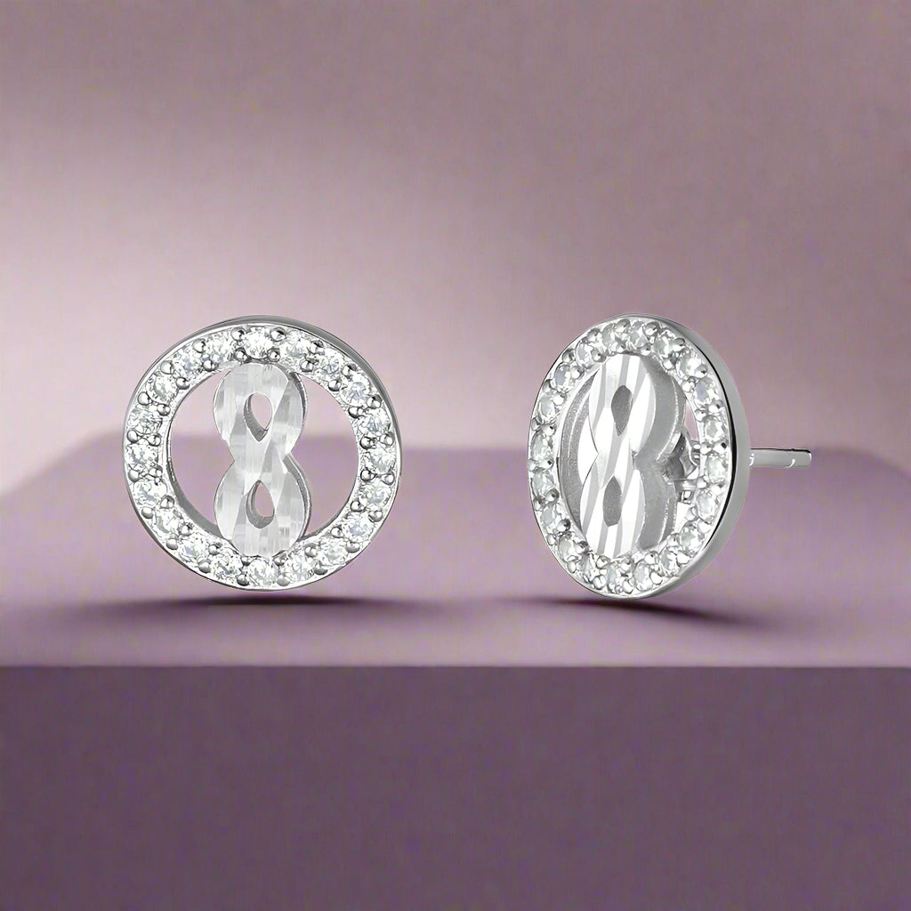 A pair of sterling silver earrings with a central cubic zirconia design and additional smaller clear crystals around it.