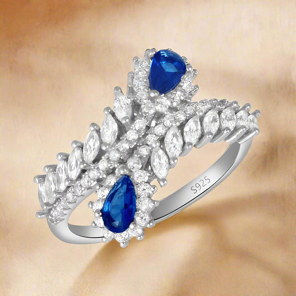 A sterling silver ring with a band, featuring a blue sapphire and clear cubic zirconia stones set in a traditional claw setting.