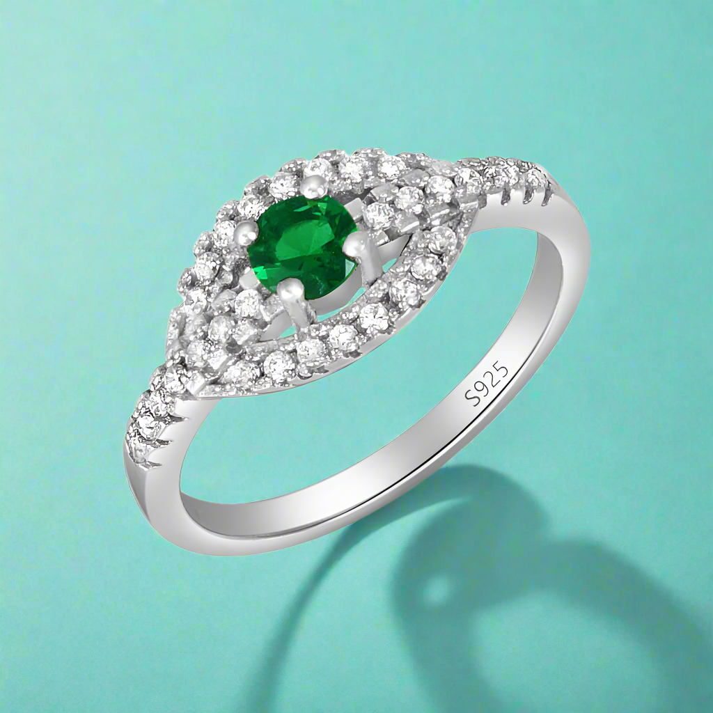 A green gemstone ring with a silver band, encrusted with cubic zirconia stones.
