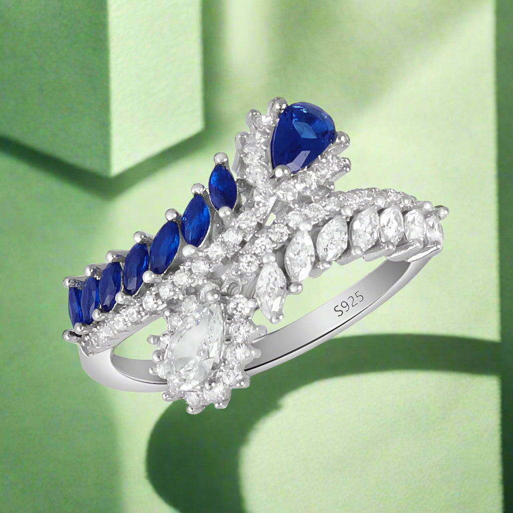 A 925 sterling silver ring with dual blue cubic zirconia stones and additional clear and white stones set in a silver setting.