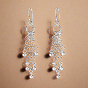 A pair of 925 sterling silver hoop earrings with a geometric pattern, dangling and sparkling in light.
