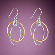 A pair of two-tone round 925 sterling silver hook earrings with one earring featuring gold-colored loops and silver-colored loops on the other, displayed against a white background.
