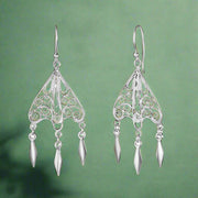A pair of sterling silver hoop earrings with intricate tribal patterns and dangling embellishments.