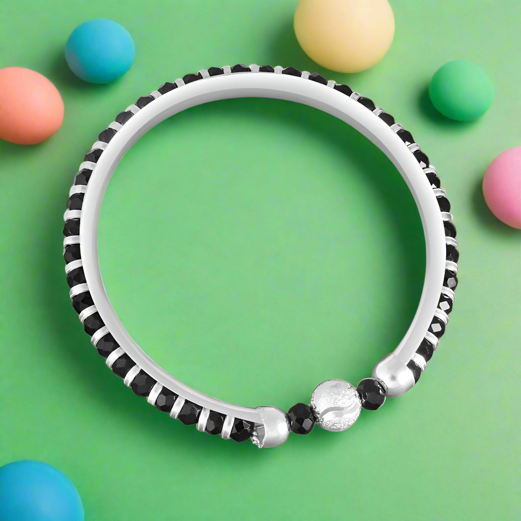 A 925 silver baby kada bangle with black beads and a single silver bead in the center, intended for newborns to 2 years old.