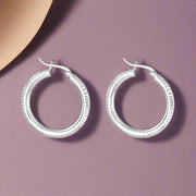 A pair of Mukti 925 sterling silver hoop earrings with a two-tone design, displayed against a white background.