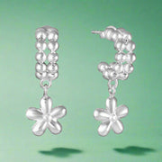A pair of sterling silver hoop earrings with dangling flower-shaped embellishments.