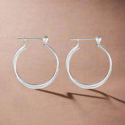 A pair of intertwined plain silver hoop earrings.