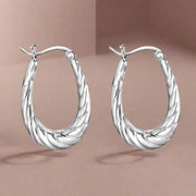 A pair of sterling silver hoop earrings with a twisted design, displayed against a white background.