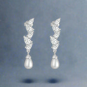 A pair of silver earrings studded with cubic zirconia and pearl accents, set in a classic hoop design.