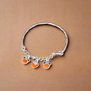 A silver bracelet with three orange and white bead charms, designed for children.
