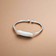 A 925 silver bracelet designed for children, featuring a simple, elegant band with a small, decorative element on one side.