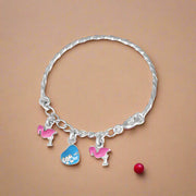A silver bracelet with a series of round charms featuring pink and blue flamingo designs, designed for kids.