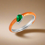 A sterling silver ring with a kaleidoscope-like pattern, featuring a green cubic zirconia center stone set in a silver band with orange accents.