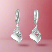 A pair of silver heart-shaped earrings with intricate detailing and small diamond-like accents.