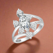 A silver ring with a central cubic zirconia stone surrounded by smaller clear crystals set in a white gold-colored band.