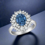 Load image into Gallery viewer, A 925 sterling silver ring with a central blue cubic zirconia stone surrounded by smaller clear cubic zirconia accents.
