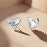 Load image into Gallery viewer, A pair of 925 sterling silver earrings in the shape of hearts, with the word &#39;LOVE&#39; written on one and adorned with sparkling zircons.

