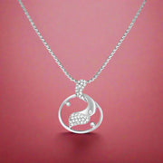 A silver pendant featuring a crescent moon design with cubic zirconia embellishments, attached to a chain.