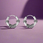 Load image into Gallery viewer, Pair of silver hoop earrings with intricate designs on a white background
